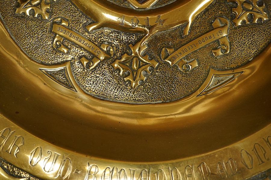 An embossed brass arts and crafts alms charger with inscriptions, 51cm in diameter